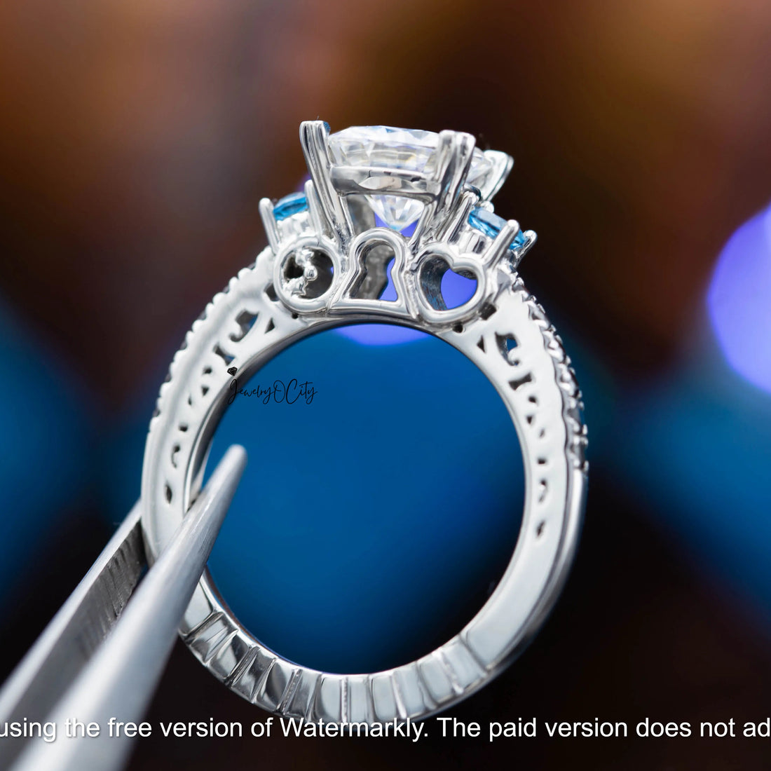 Silver ring with gemstones held by tweezers against a blurred background