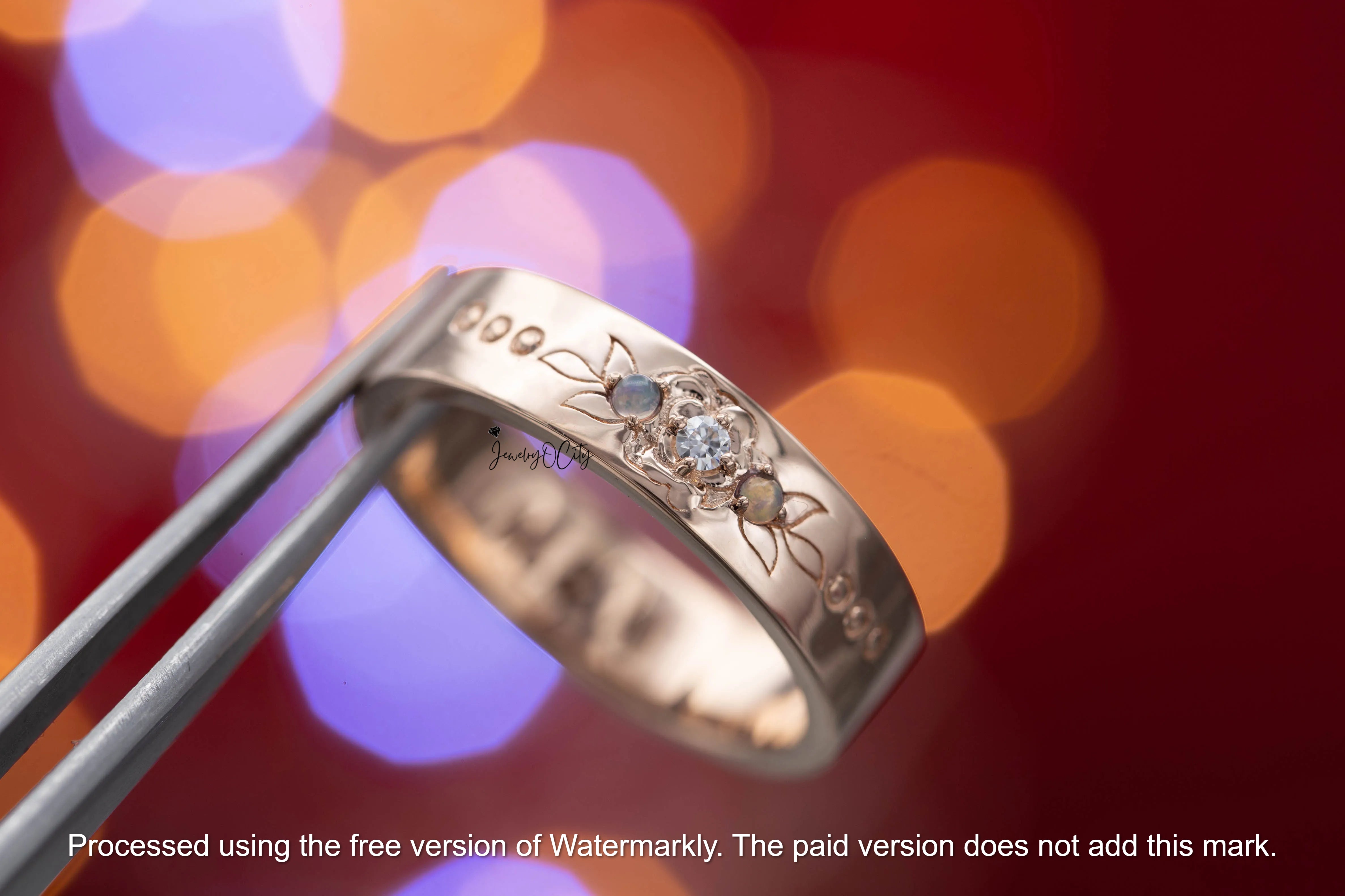 Silver ring with engraved design against a blurred colorful background