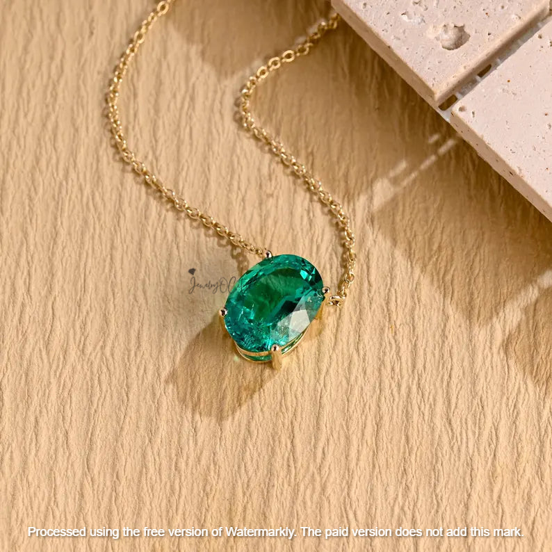 Gold necklace with a green gemstone pendant on a wooden surface