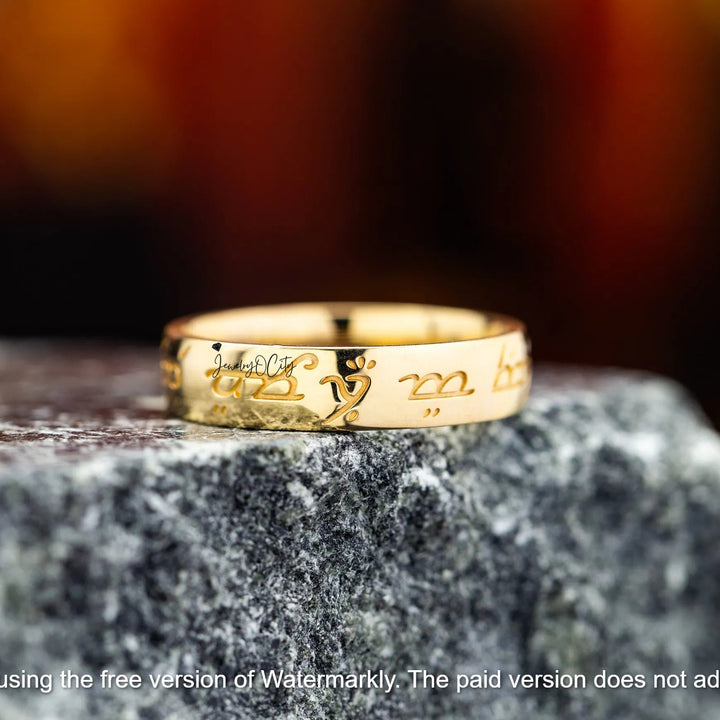 Gold ring with engraved design on a textured stone surface