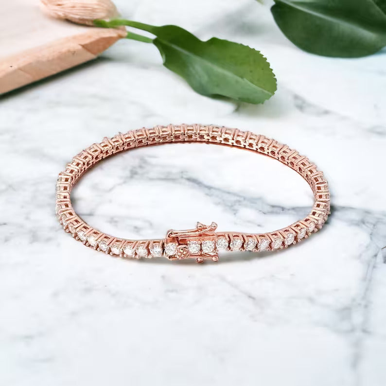 Rose gold bracelet with diamond accents on a marble surface