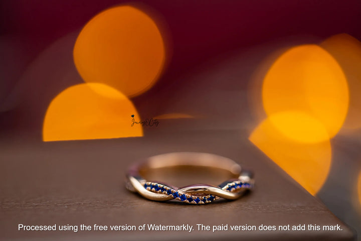 Silver ring with blue stones on a dark surface with blurred lights in the background